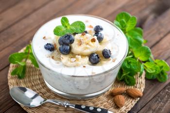 Yogurt with fresh blueberry, banana and almond nuts, delicious dessert for healthy breakfast