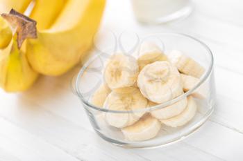 Fresh sliced bananas on white wooden background closeup, healthy eating