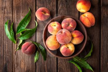 Fresh juicy peaches with leaves on dark wooden rustic background