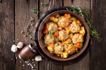 Meatballs stewed with vegetables on wooden table, top view