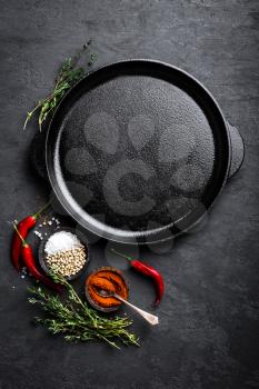 Empty cast-iron pan with ingredients for cooking on black background, top view