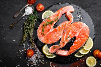 Fresh raw salmon red fish steaks on black background, top view