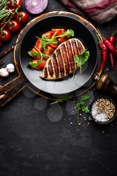 Grilled chicken fillet on black background, top view