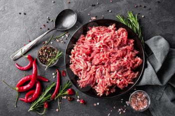 Mince. Ground meat with ingredients for cooking on black background. Top view