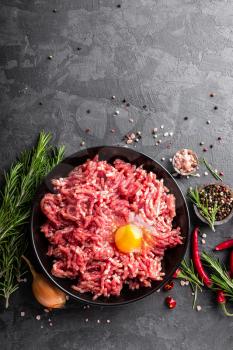 Mince. Ground meat with ingredients for cooking on black background. Top view