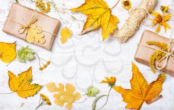 Composition of gifts and yellow leaves on a white wooden background. concept autumn