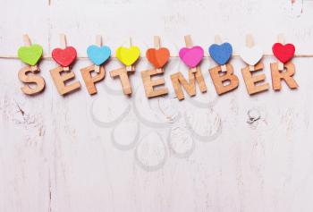 the word september   letters on a wooden clothespins on a white background old