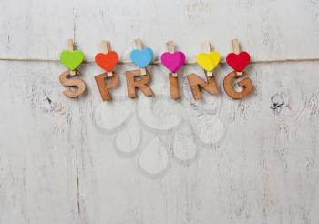 word spring and colored hearts on a white background old wooden
