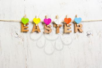 the word Easter from white letters with colored hearts clothespins on a white background old