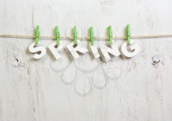 word spring with white letters with a green clothespins on a white background old