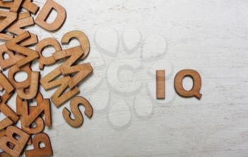 Word IQ (intelligence quotient) are made with wooden letters on an old white wooden background
