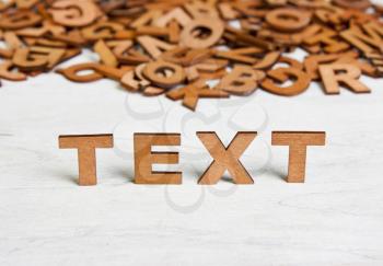 Word Text made with wooden letters on a background of other blurred letters