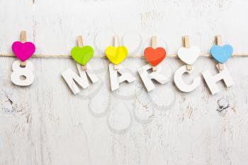 8 March from wooden letters and multicolored hearts on a white background old wooden