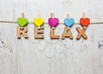 Word relax of wooden letters on a white background with wooden clothespins