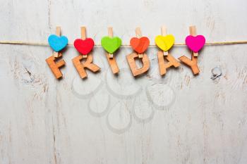 Friday word from wooden letters with colored clothespins on a white wooden background