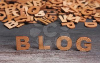 the word blog with wooden letters on a background of different letters