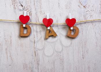 wood letters and heart forming phrase dad on old wooden white  background