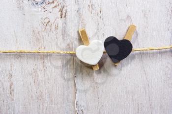 Two lovely white and Black  hearts l hanging on the clothesline. On old white wood background.