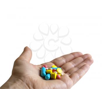 Colored pills, tablets and capsules in a hand on a white background