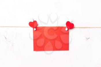 two red wooden hearts hold a sheet where you can write your greeting