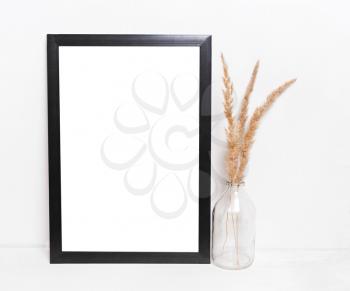 Blank black picture frames on on  white background ,with the decor of dry twigs and glass vases. Mockup in hipster style workspace