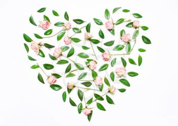 Pink flowers, green leaves in the shape of a heart on a white background. The concept of a holiday of love. Top view, flat