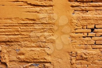 Old , yellow,Orange destroyed plaster at a brick wall. Grunge cement, with a shabby paint background.