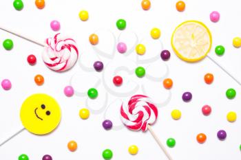 Lollipops, candy smile on, are scattered around the colorful jelly beans on a white background. flat. 