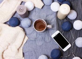 Cup of coffee, cocoa and candles, phone and garlands on a stylish background, top view, flat