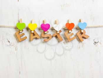 Easter word made of  letters with colored hearts clothespins on a white background old