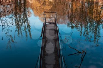 Old, rusty, iron bridge on the lake, sea, reflection of trees