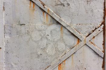 Cross on metal doors, a background of gray, cracked paint, iron texture and rust