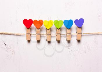Wooden hearts of rainbow colors on clothespins on a white background. The symbol of LGBT 