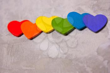 Wooden hearts of the color of the rainbow on a gray background. symbol of LGBT