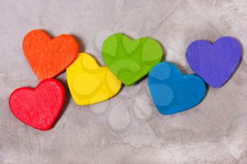 Wooden hearts of the color of the rainbow on a gray background. LGBT symbol