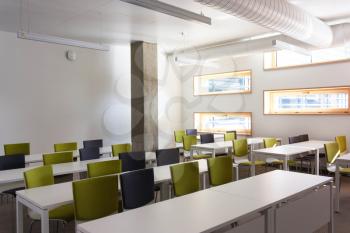 Empty Study room, class for students .. White tables, walls and green armchairs.Style high-tech
