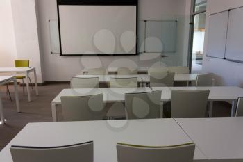 Training empty cabinet, class for students with a board on the wall .. White tables, walls and green armchairs.Style high-tech