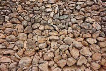  wall of rough cobblestones in a row, a brown background of natural stones