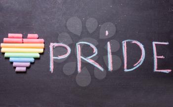 The heart of the colors of the rainbow and the word pride is written in chalk. The LGBT Symbol