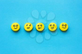 Yellow pills with smiles on a blue background. The concept of treatment, positive, depression