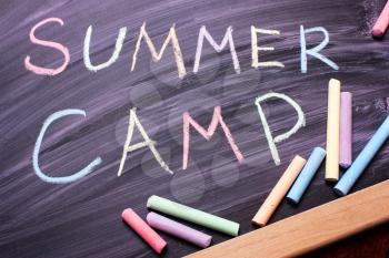 Words SUMMER CAMP written with colorful chalk on blackboard.Top view, flat.Vacation Concept. recreation