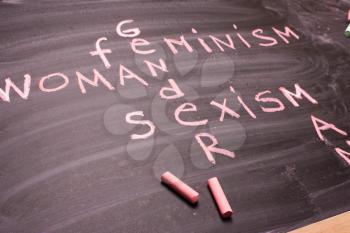 Words gender, sexism, feminism written in pink chalk on a chalkboard