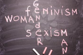 Words gender, sexism, feminism written in pink chalk on a chalkboard