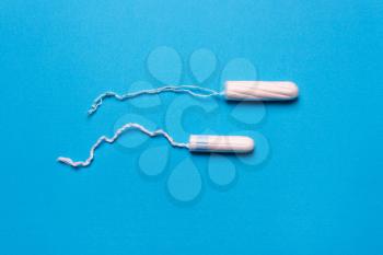 tampon on a blue background. The view is flat. Concept of critical days, menstruation