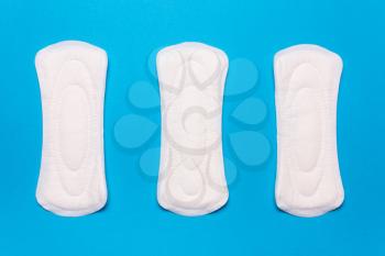 three menstrual pads on a blue background. Concept of critical days, menstrual cycle, menstruation