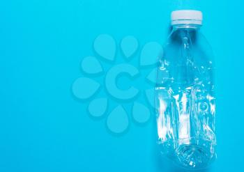 Transparent plastic bottle on a blue background..The concept of sorting polyethylene, household waste. Protection of the environment, ecology