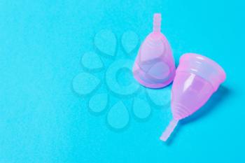 Pink menstrual cup on a blue background. Concept of women's health, hygienic means of protection, menstruation, ecology of the planet.