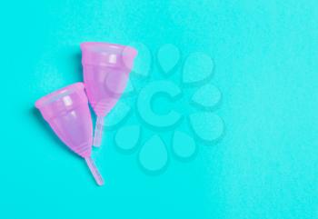 Two pink menstrual cup on a blue background. Concept of women's health, hygienic means of protection, menstruation, ecology of the planet.