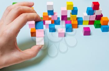 Blue, pink and white cube in hand. Concept of logical thinking, development, creativity, diversity