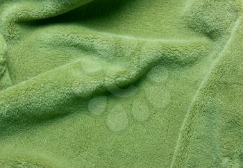 Green soft  fleece texture. The surface of a teddy crumpled microfiber rug